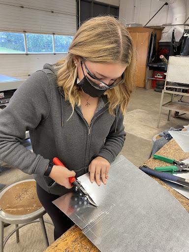 SMDCVI grade 12 student Jenna Switzer using tin snips to cut out a piece for her ductwork