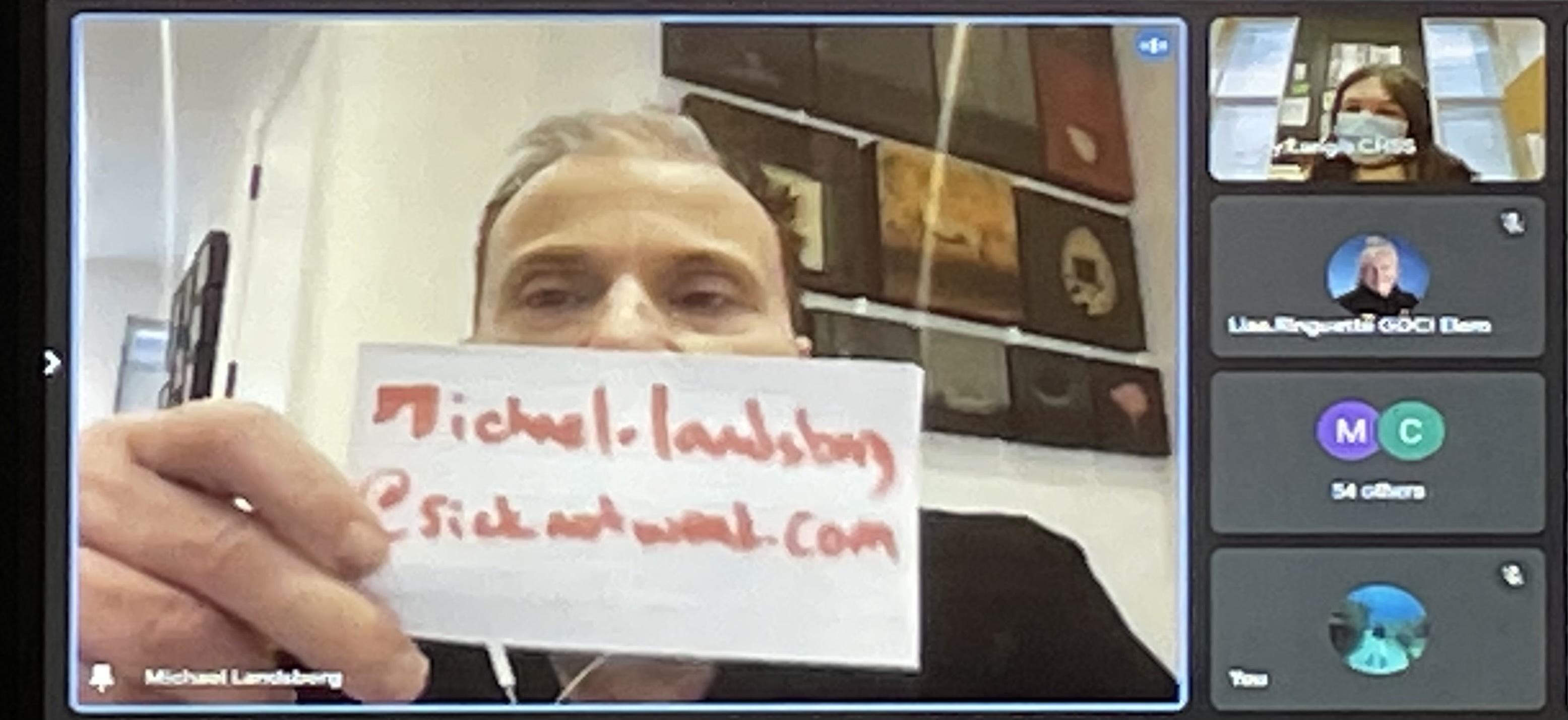 Screenshot of video conference showing Michael Lansberg holding up a piece of paper that reads #sicknotweak