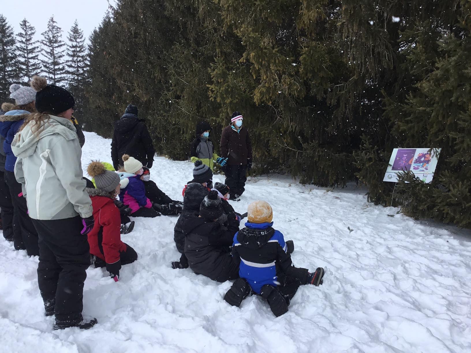 Photo showing students in winter gear on school grounds, looking at sign containing part of a story