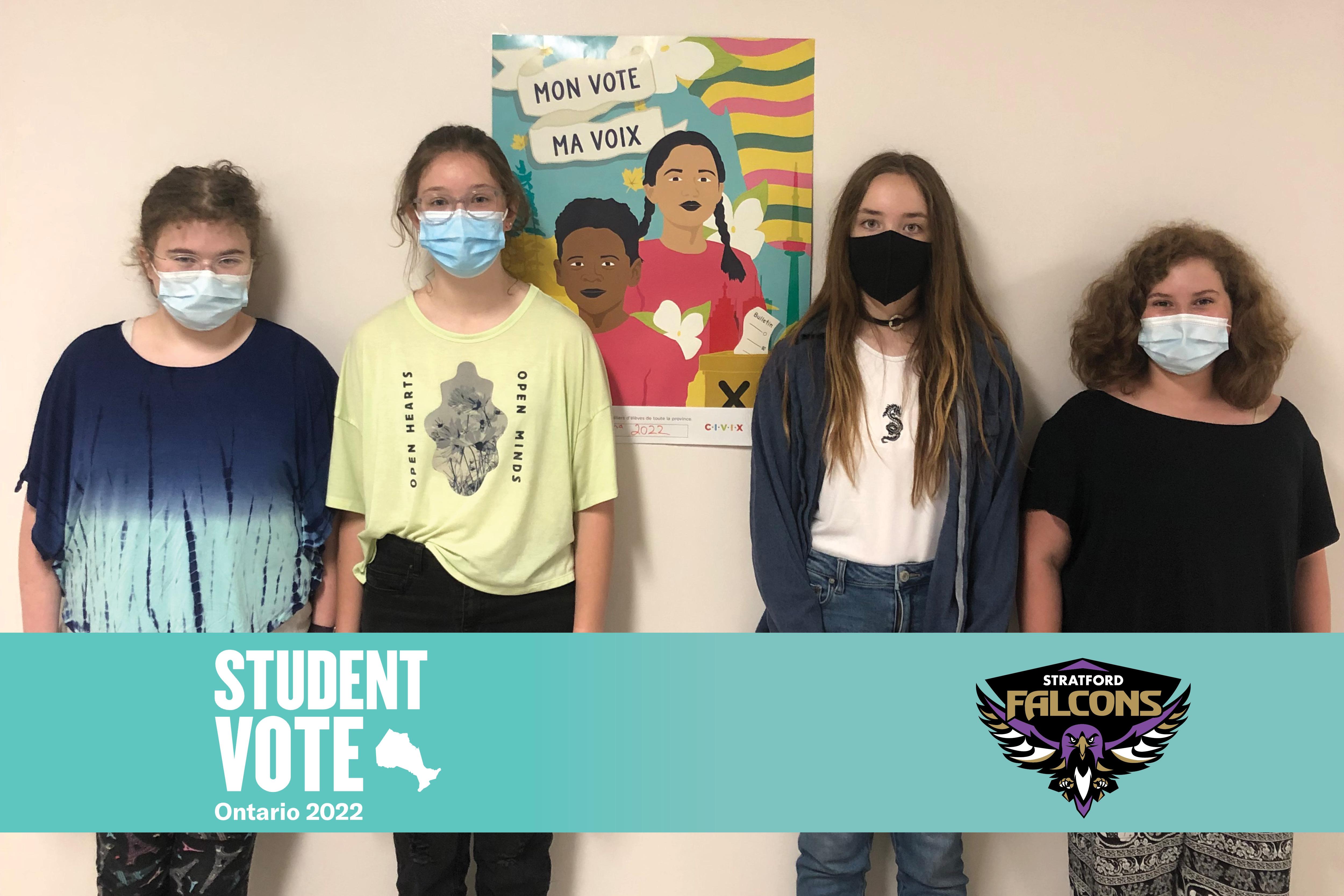 Photo of four students standing in hallway beside poster with text “Mon vote, ma voix.” Turquoise banner with Student Vote Ontario 2022 logo and Stratford Falcons logo.