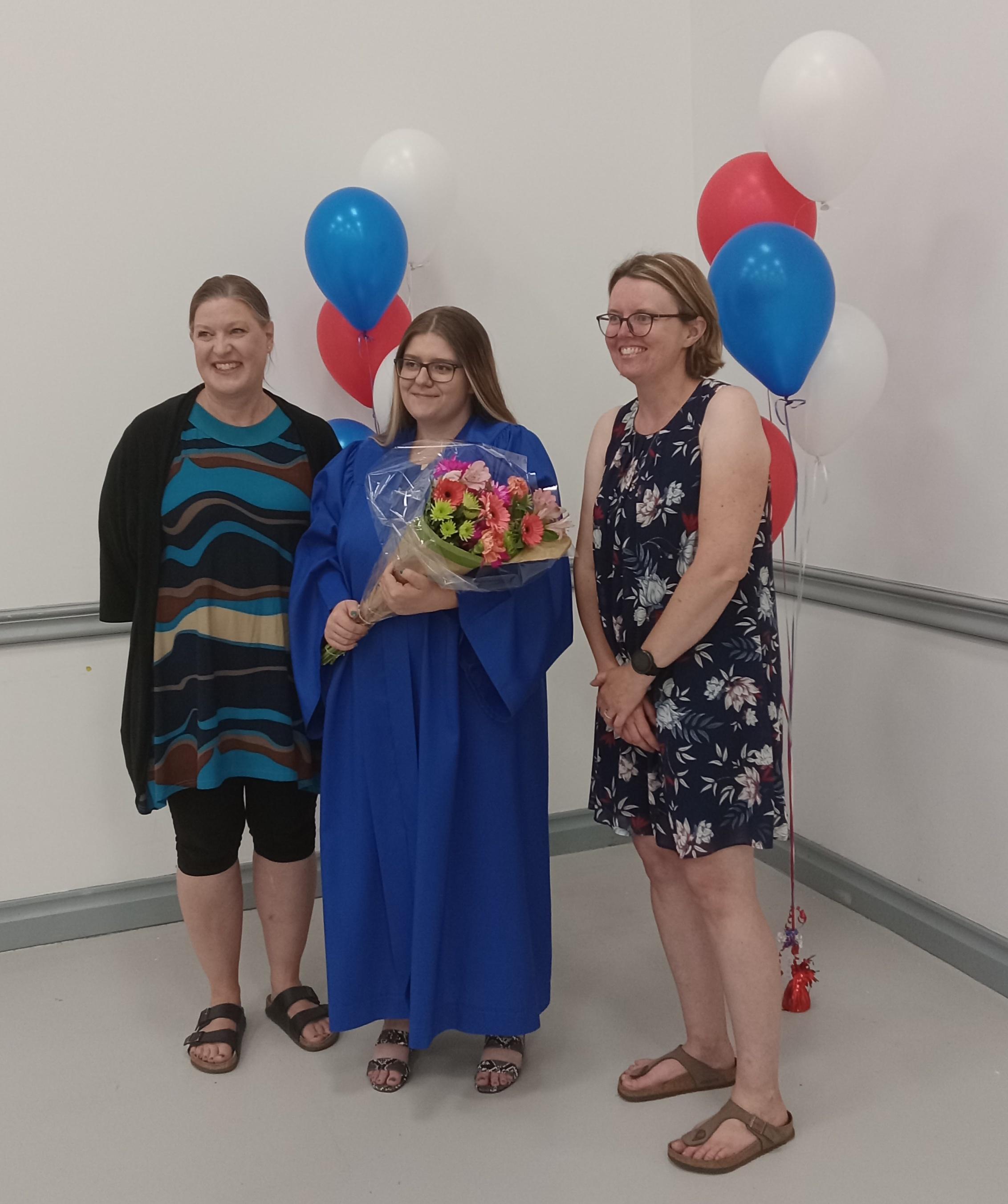 Graduate Sky poses in her gown with Kendra Brohman and Erin Jones