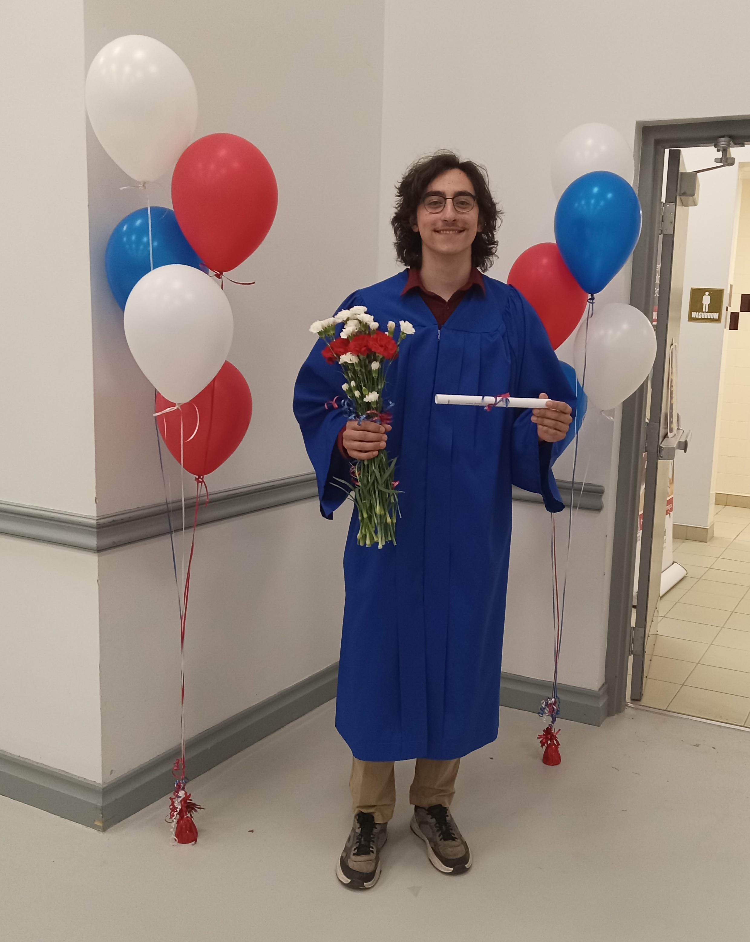 Judah poses in front of red, blue, and white balloons